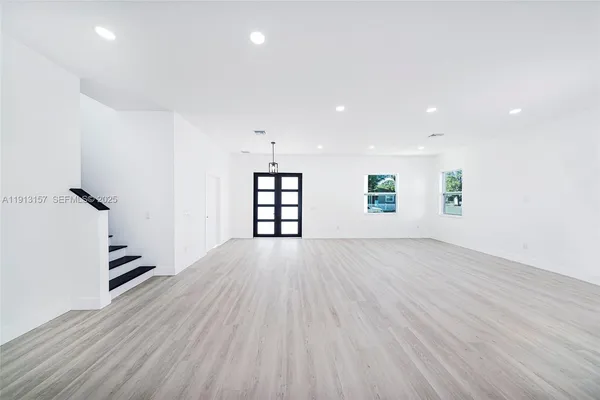 an empty room with wooden floor cabinet and windows