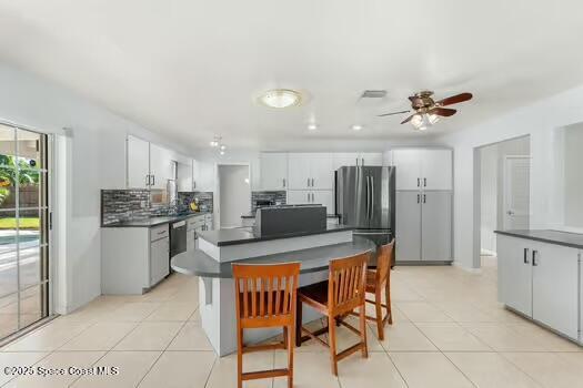 933 Waialae Circle Northeast Palm Bay, FL 32905 - Photo 13 of 32 a kitchen with stainless steel appliances kitchen island granite countertop a table chairs and a refrigerator