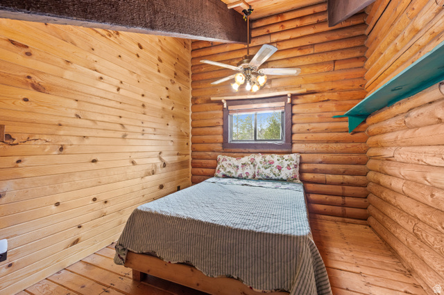 4725 Pine Ridge Road Evanston, UT 82930 - Photo 45 of 82 Rustic interior featuring log walls, wood-finish flooring, and a ceiling fan with integrated lighting