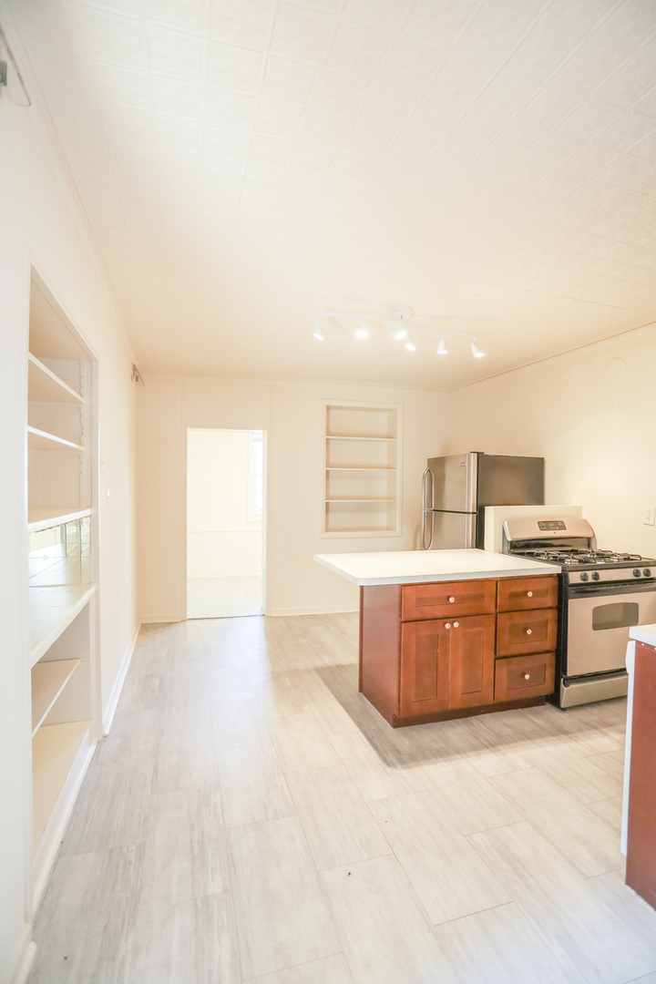 2315 West School Street, Unit G Chicago, IL 60618 - Photo 4 of 12 a large kitchen with kitchen island a sink wooden floor and stainless steel appliances