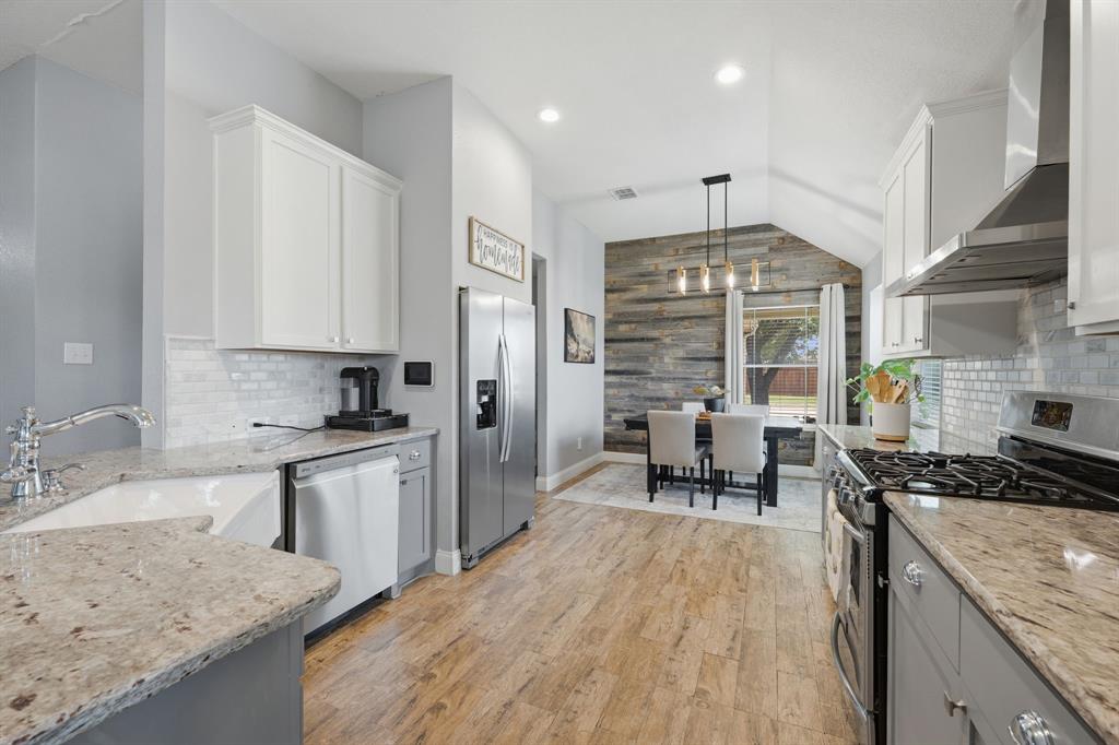 14152 Rodeo Daze Drive Fort Worth, TX 76052 - Photo 6 of 20 Kitchen featuring wood-finish flooring, white cabinetry, granite countertops, a farmhouse sink, and stainless steel appliances including a refrigerator and gas range