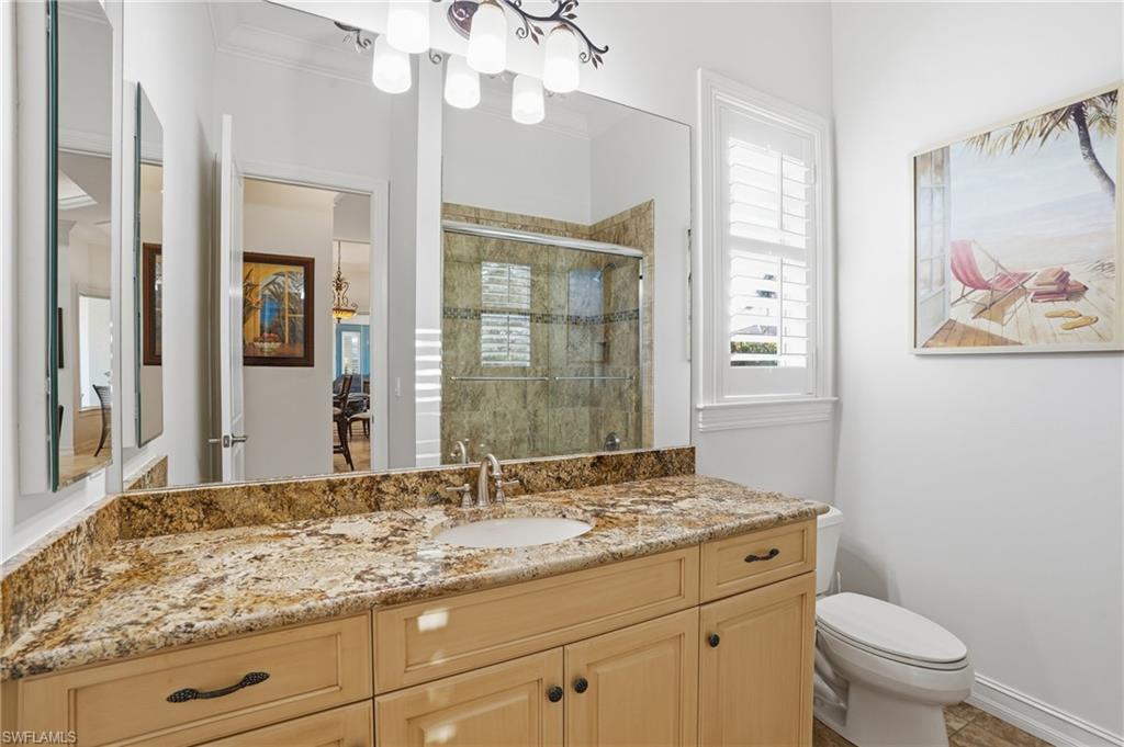 430 Saddlebrook Lane Naples, FL 34110 - Photo 20 of 37 a bathroom with a granite countertop sink a toilet a mirror and a shower