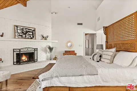 a bedroom with a bed a fireplace and windows