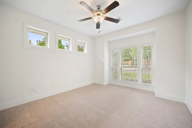 an empty room with windows and chandelier fan