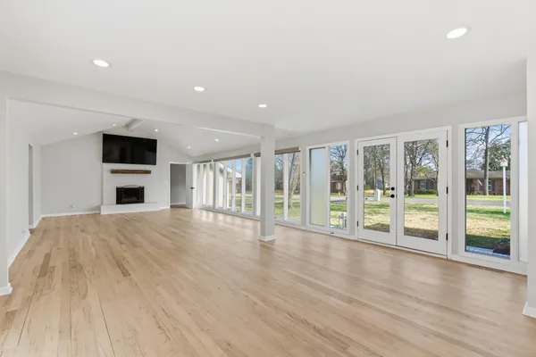 a view of an empty room with wooden floor and a fireplace