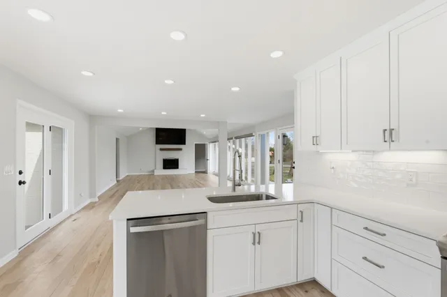 a view of an empty room with wooden floor and a kitchen