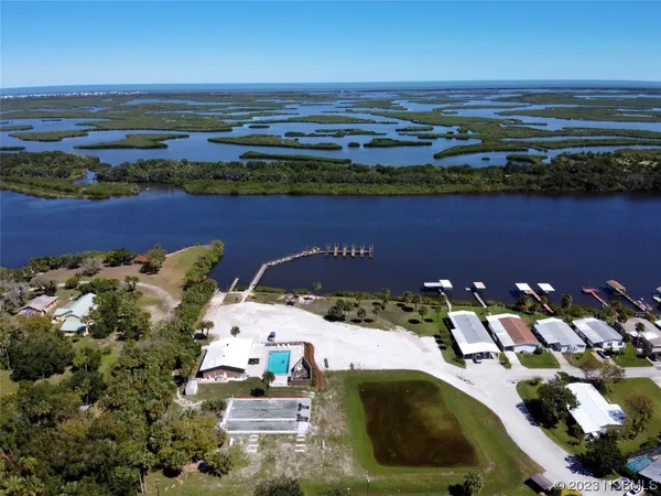 an aerial view of ocean and residential houses with outdoor space