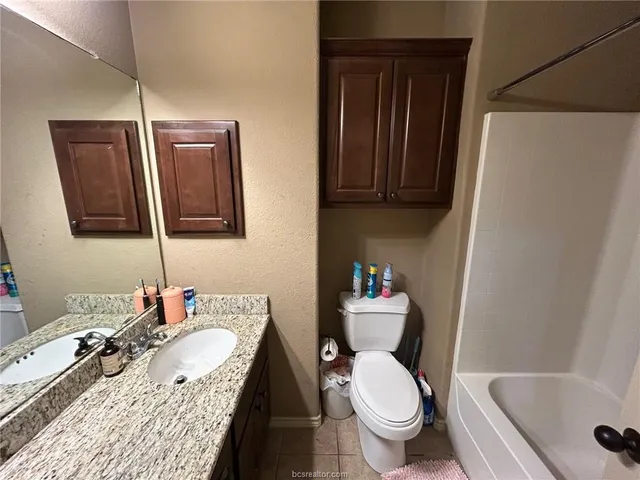 a bathroom with a granite countertop toilet sink and mirror