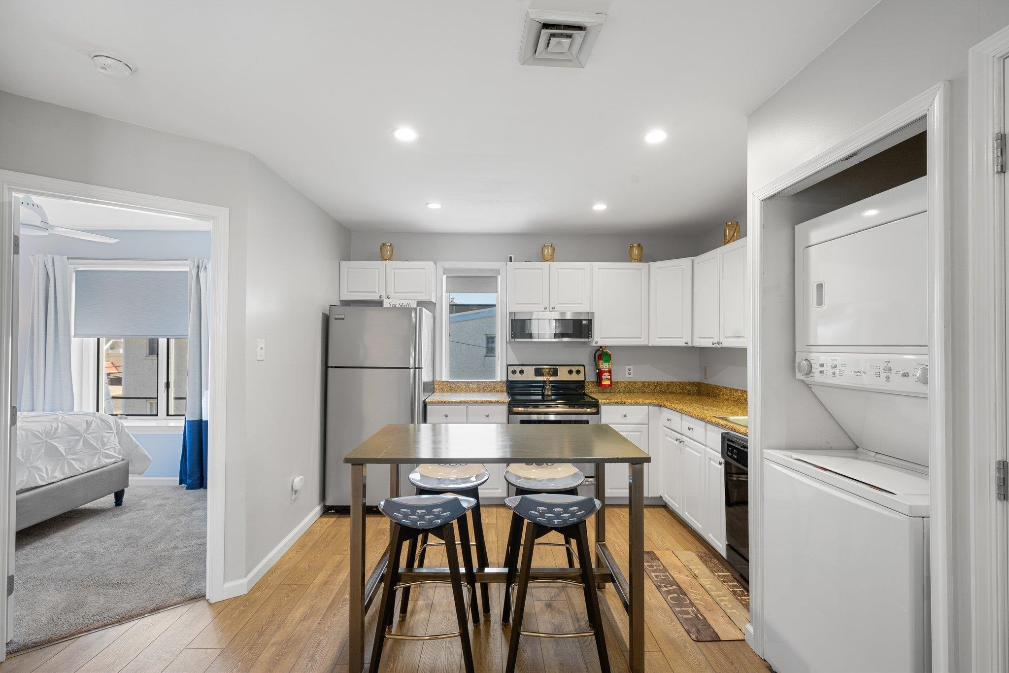 177 80th Street, Unit 304 Avalon, NJ 08202 - Photo 23 of 31 a kitchen with a table chairs refrigerator and microwave
