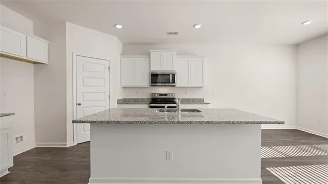 a kitchen with granite countertop white cabinets and stainless steel appliances