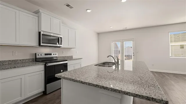 a kitchen with granite countertop a sink and white cabinets