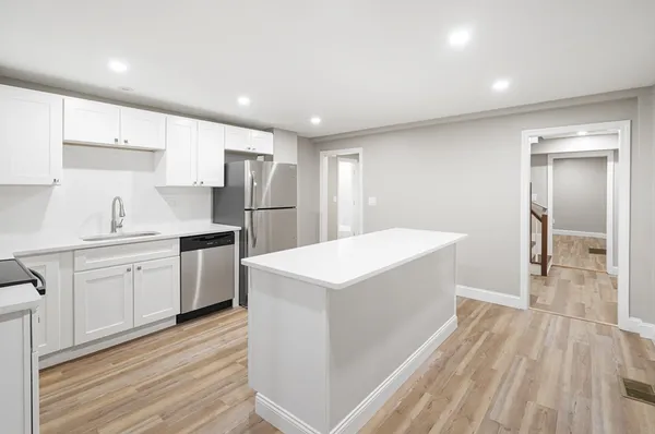 a kitchen with a sink a refrigerator and white cabinets