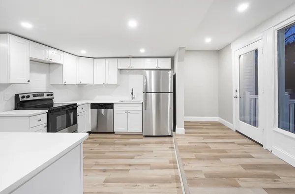 a kitchen with a refrigerator a stove top oven and white cabinets
