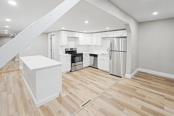 a kitchen with a refrigerator a stove top oven and white cabinets