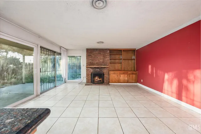 a view of empty room with floor to ceiling window and fireplace