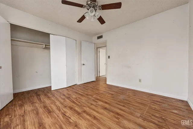 a view of an empty room and chandelier fan