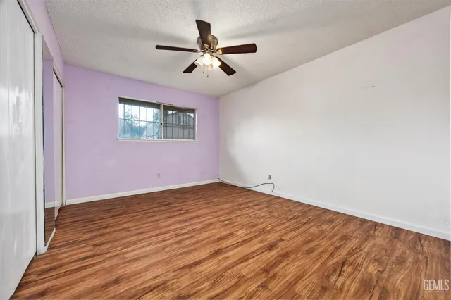 an empty room with wooden floor fan and windows