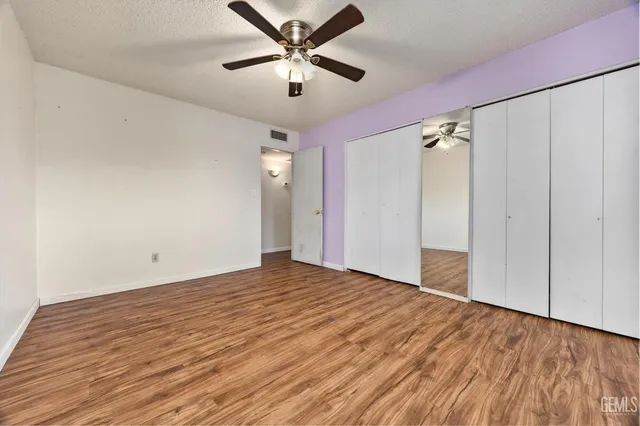 an empty room with wooden floor closet and ceiling fan