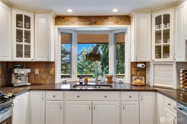 a kitchen with stainless steel appliances granite countertop white cabinets and a window