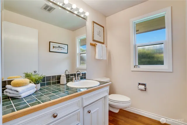 a bathroom with a granite countertop sink mirror vanity and toilet