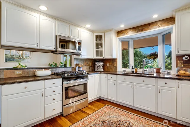 a kitchen with stainless steel appliances granite countertop a stove a sink and a microwave