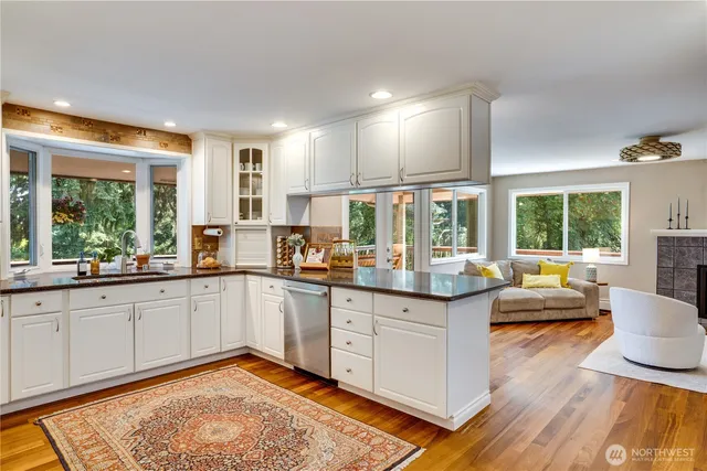 a kitchen with granite countertop lots of white cabinets and wooden floor