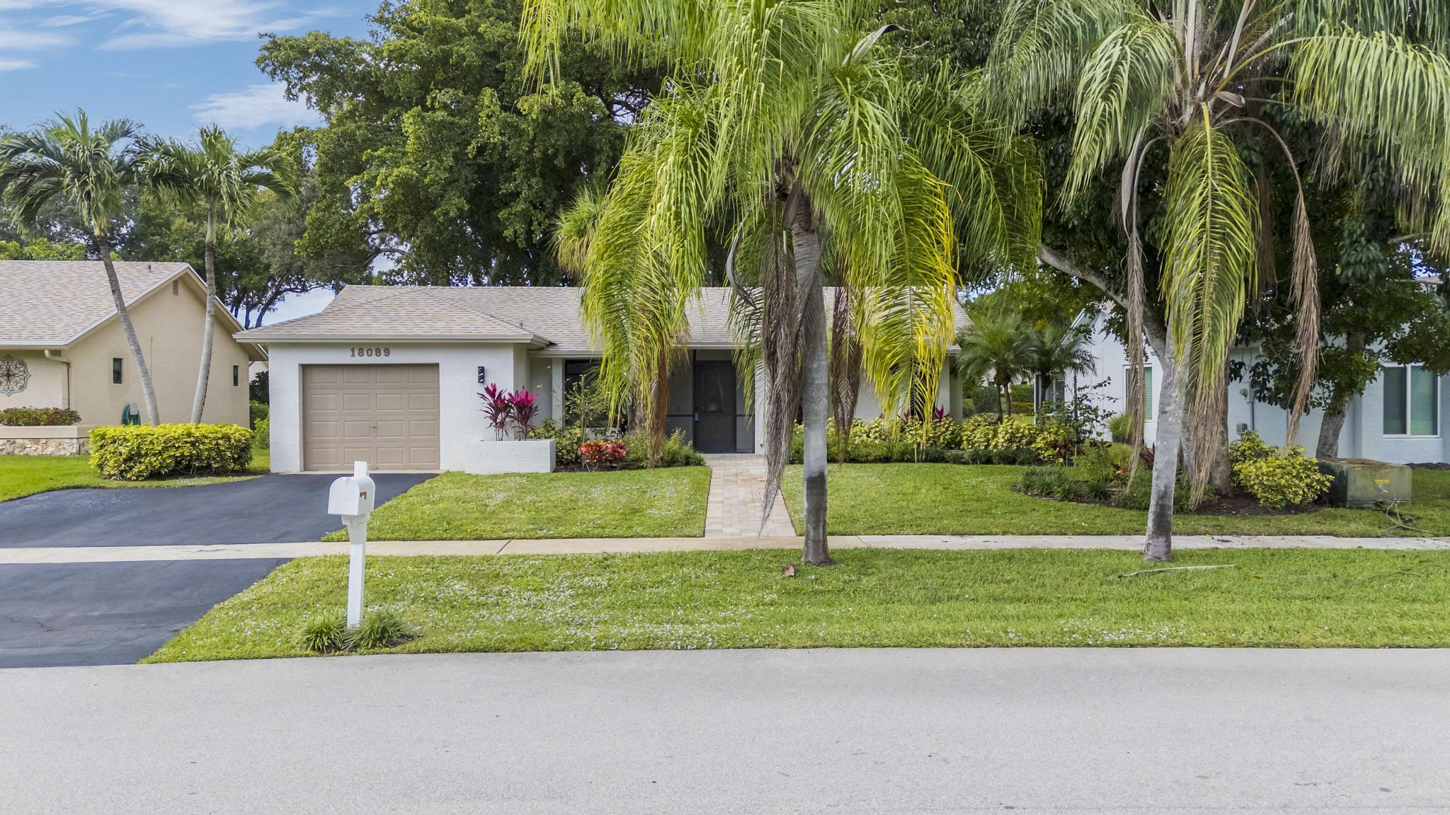 18089 103rd Trail South Boca Raton, FL 33498 - Photo 5 of 51 a front view of a house with a yard and palm trees