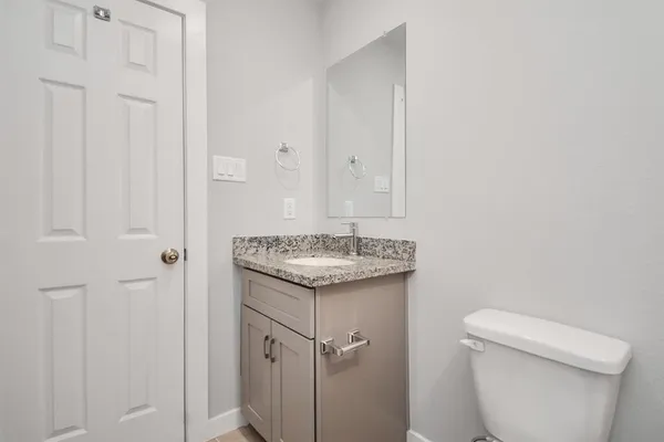 a bathroom with a granite countertop sink and a toilet
