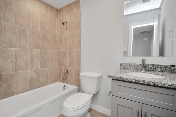 a bathroom with a granite countertop toilet a sink and a bathtub