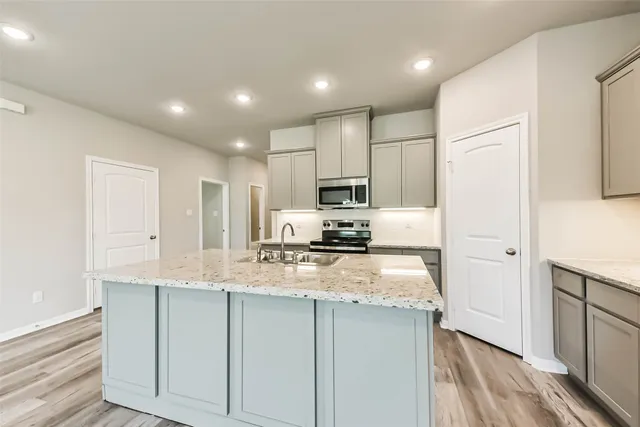a kitchen with kitchen island granite countertop appliances cabinets a sink and a counter top space