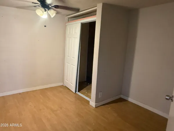 an empty room with closet and a ceiling fan