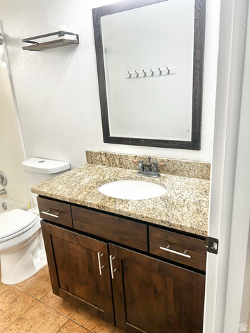 570 250 East Parowan, UT 84761 - Photo 14 of 27 Bathroom vanity featuring a granite countertop with an undermount sink, dark wood-finish cabinetry with silver hardware, and a framed mirror