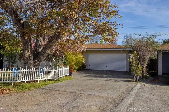 a view of a house with a small yard and a large tree