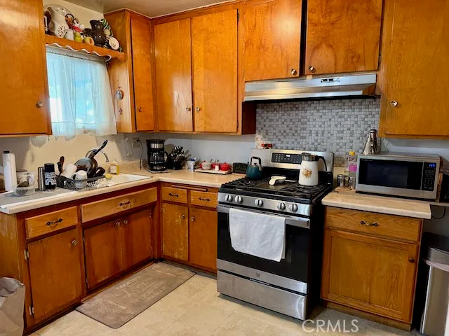 a kitchen with stainless steel appliances granite countertop a stove a sink and a microwave