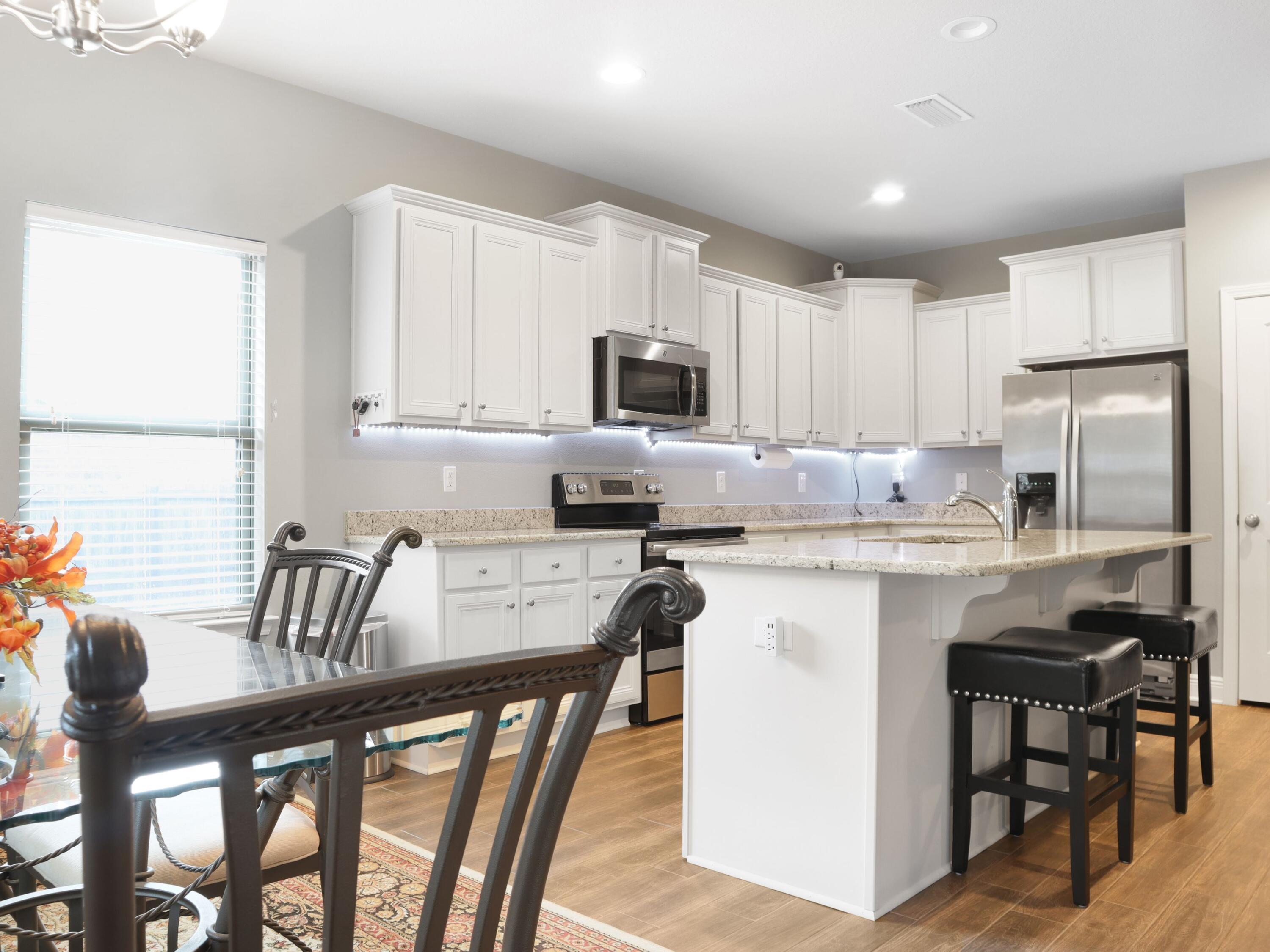 4753 Dupont Circle Pace, FL 32571 - Photo 15 of 42 a kitchen with stainless steel appliances granite countertop a stove top oven a refrigerator a sink and a dining table with white cabinets