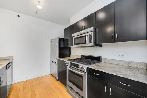 a kitchen with granite countertop cabinets stainless steel appliances and wooden floor