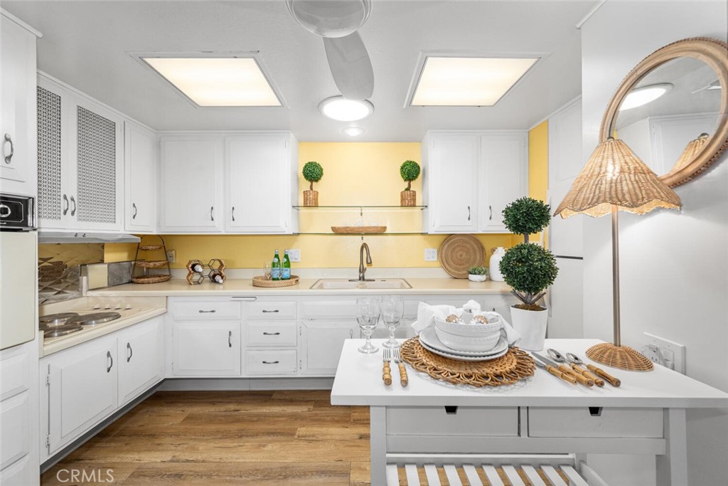 1121 Northwood Road, Unit 237D M9 Seal Beach, CA 90740 - Photo 23 of 45 a kitchen with a sink stove and white cabinets with wooden floor