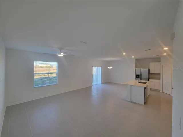 an empty room with kitchen view and windows