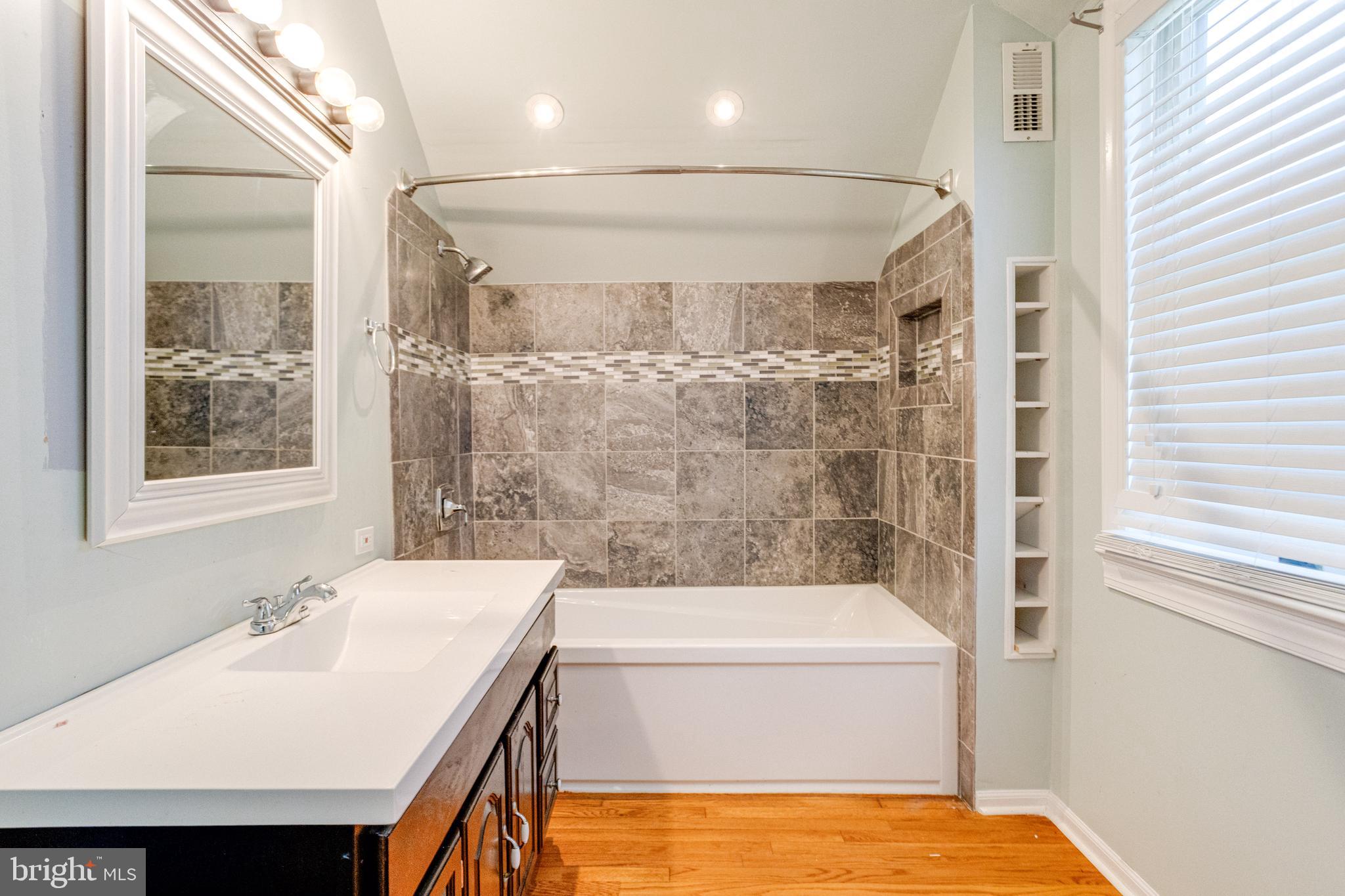 8421 Old Harford Road Parkville, MD 21234 - Photo 41 of 44 a bathroom with a tub a sink and a large mirror