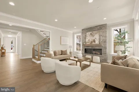 a living room with stainless steel appliances furniture a rug kitchen view and a large window