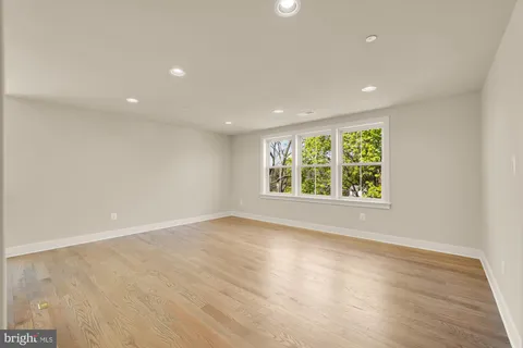 a view of an empty room with wooden floor and closet