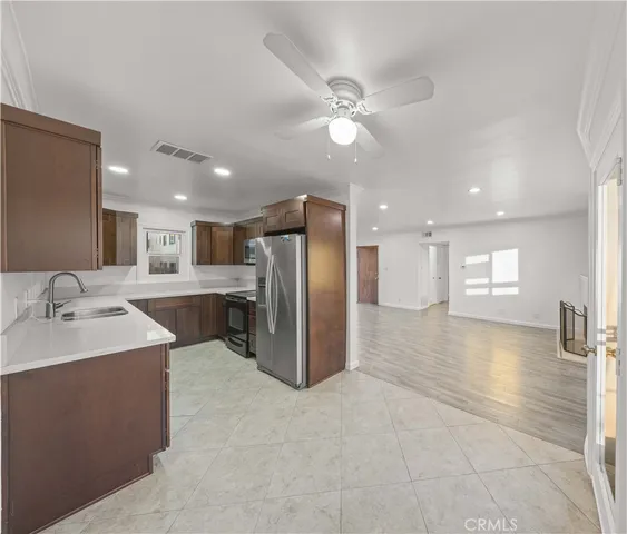 a large kitchen with a large counter top a sink stainless steel appliances and cabinets