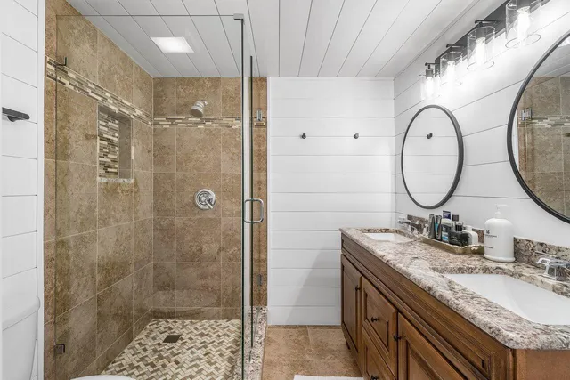 a bathroom with a granite countertop sink a mirror and a shower