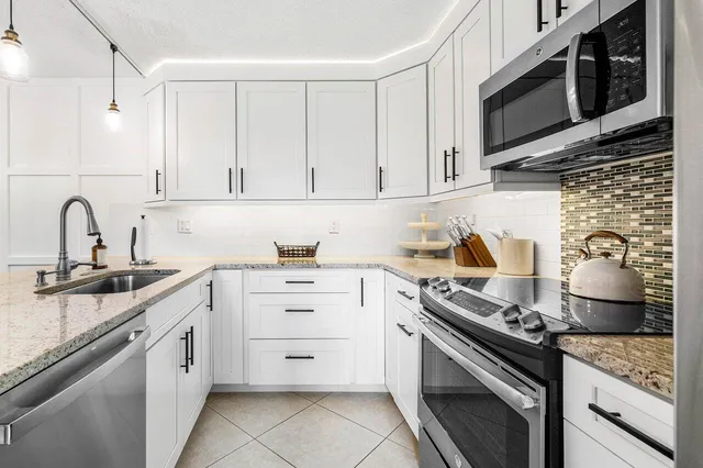 a kitchen with stainless steel appliances granite countertop white cabinets and stove