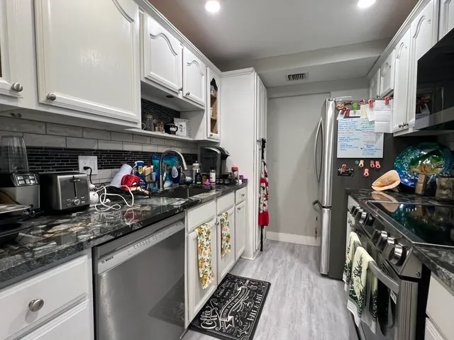 a kitchen with stainless steel appliances granite countertop a refrigerator a stove top oven a sink and dishwasher