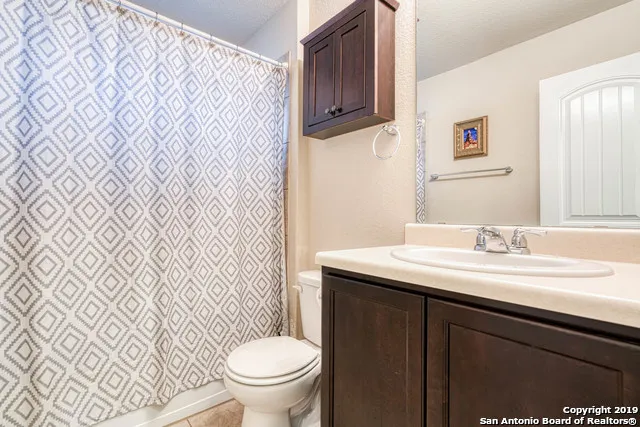 a bathroom with a granite countertop sink and a toilet