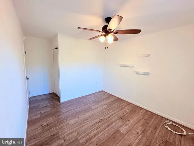 an empty room with wooden floor fan and windows