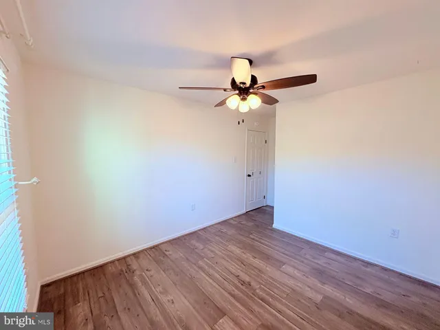a view of a small space with wooden floor and a fan