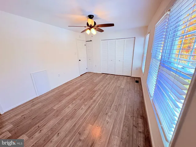 a view of empty room with wooden floor and fan