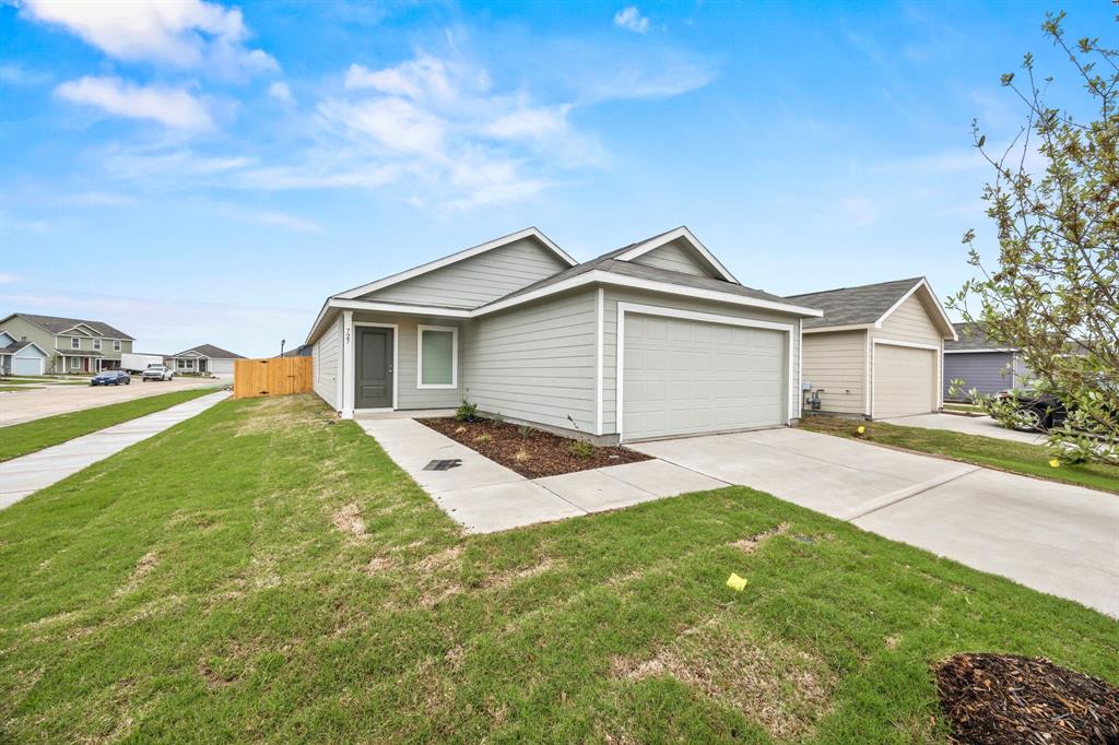 Ranch-style home with an attached garage, driveway, fence, and a front lawn